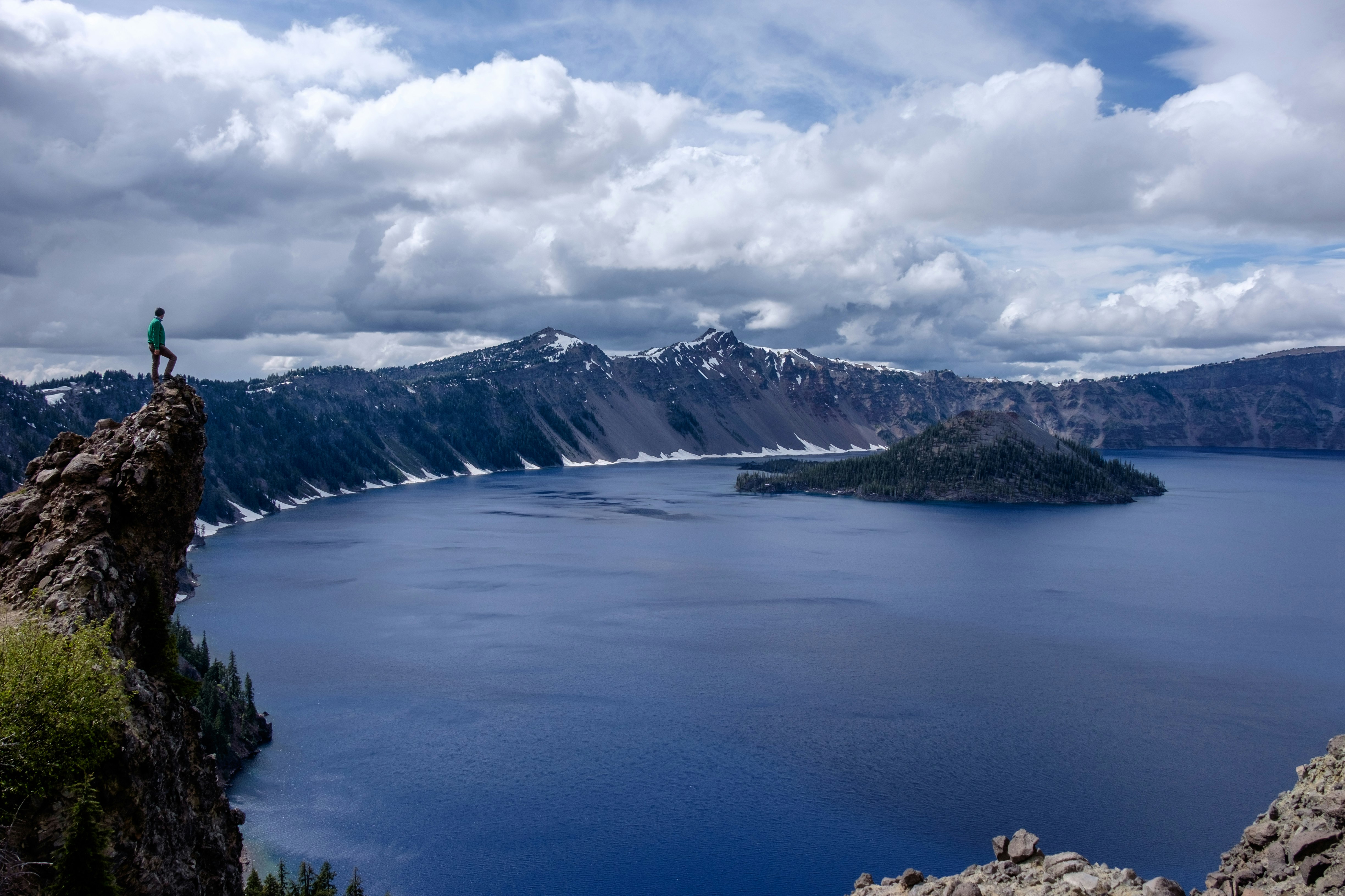 man standing on lake cliff near mountain alps